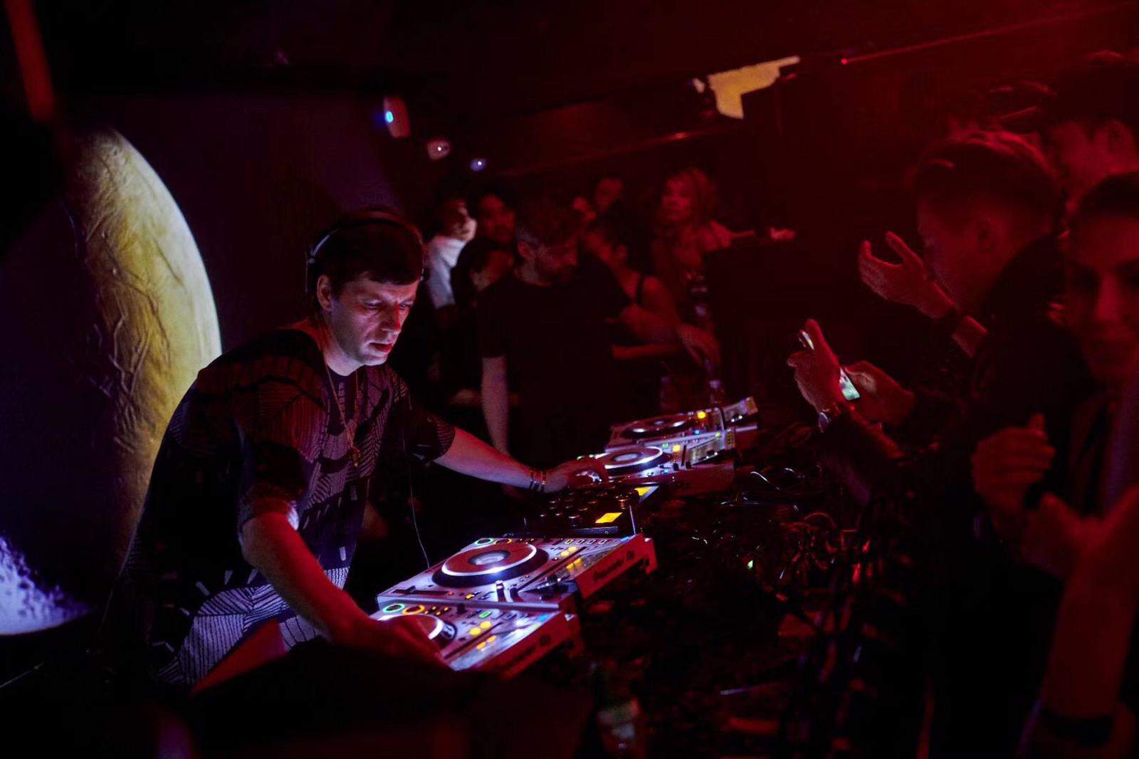 A DJ at the decks in the dark club