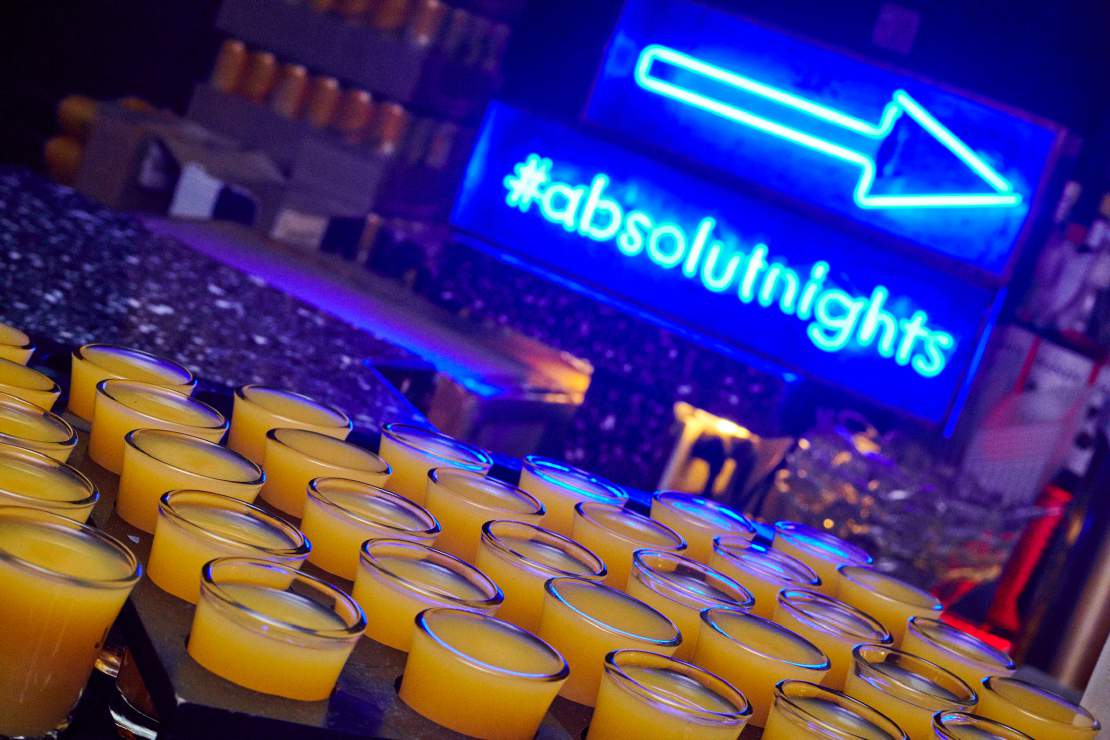 An ABSOLUT night sign above rows of glasses
