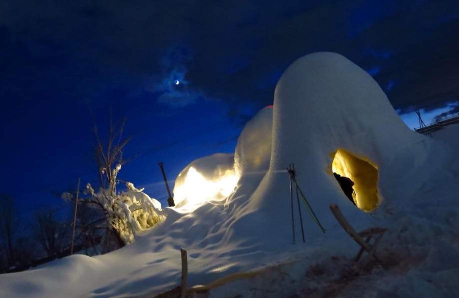 A snow igloo at night with a lit entrance